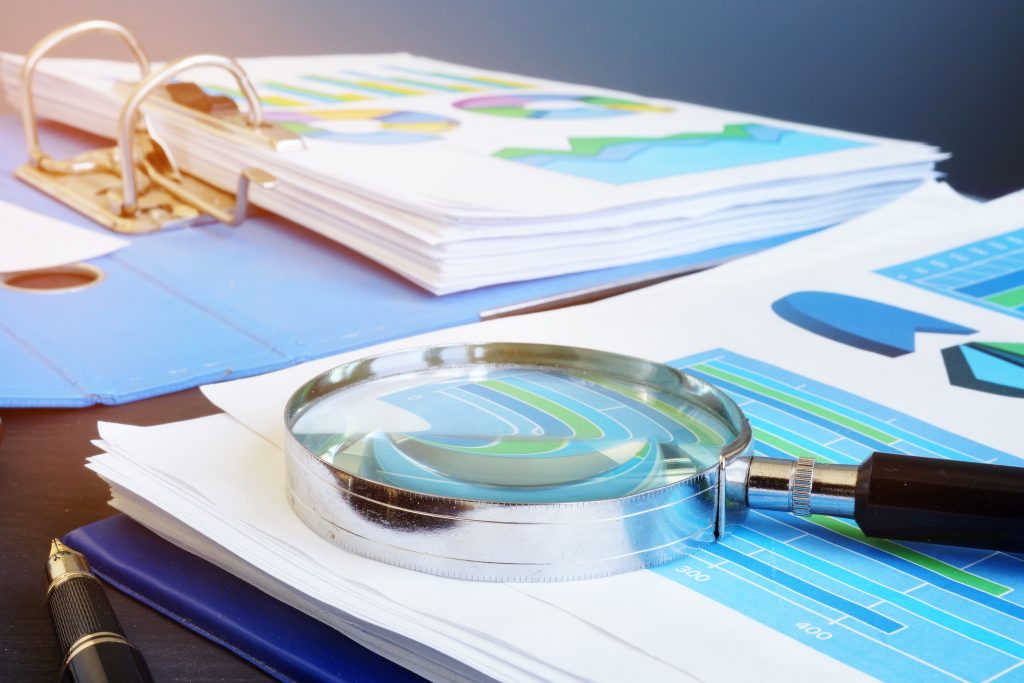 Financial audit report and magnifying glass on a desk.