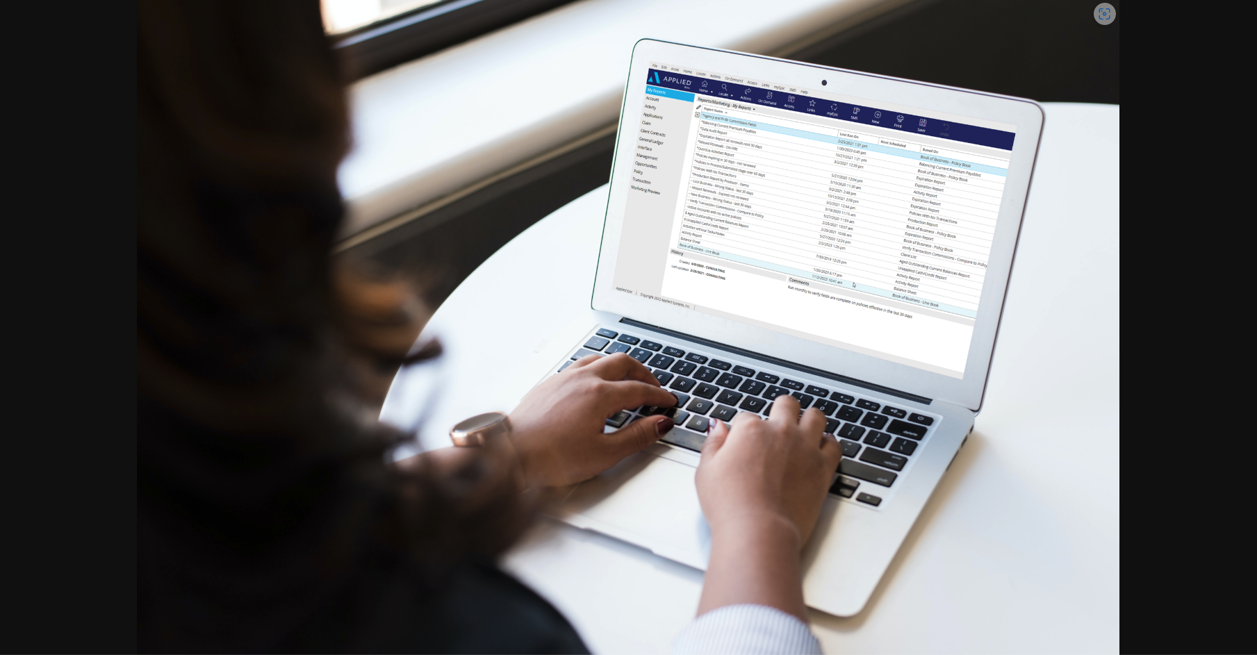 insurance professional looking at Applied Epic reports on a laptop